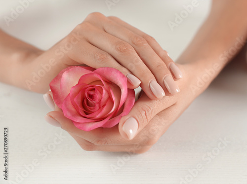 Woman holding flower at table, closeup. Spa treatment