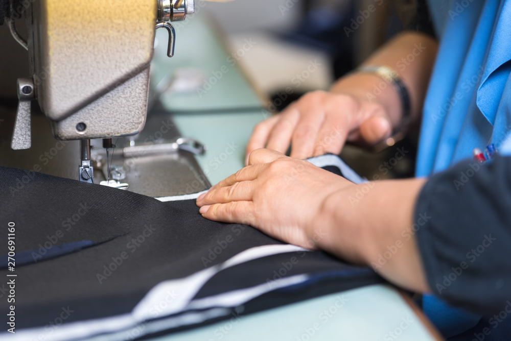 Seamstress sews clothes on a sewing machine. Textile factory .
