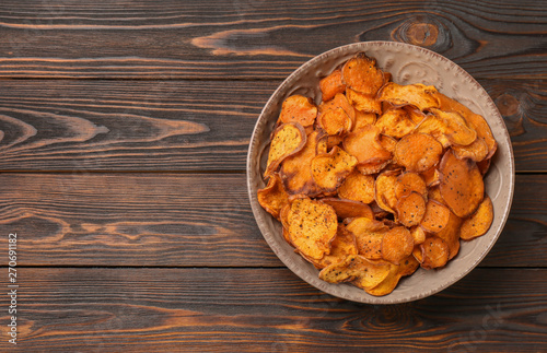 Plate of sweet potato chips on wooden table, top view. Space for text