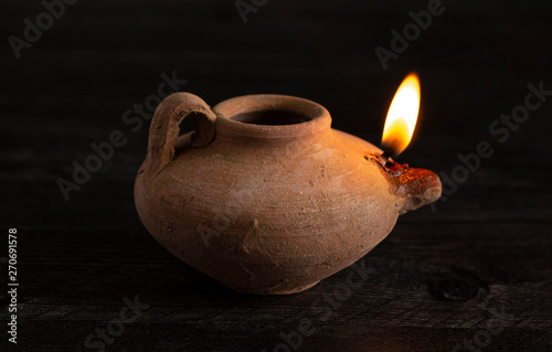 Schilderij op canvas A Lit Handmade Oil Lamp from the Middle East on a Dark Table