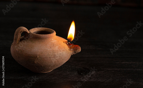 A Lit Handmade Oil Lamp from the Middle East on a Dark Table photo