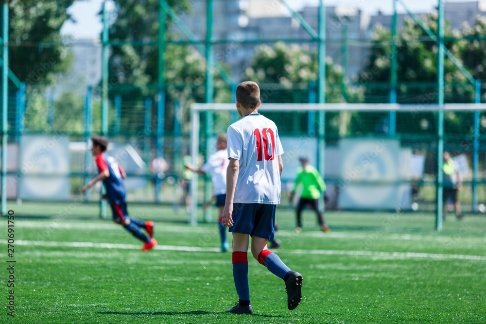 Obraz premium Boys at blue white sportswear run, dribble, attack on football field. Young soccer players with ball on green grass. Training, football, active lifestyle for kids