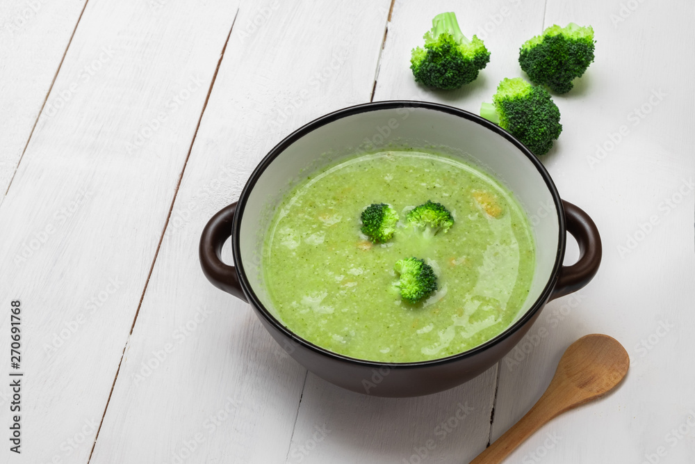 Bowl of broccoli cream soup on white wooden background. Image with copy space. Bowl of broccoli cream soup on white wooden background. Image with copy space.