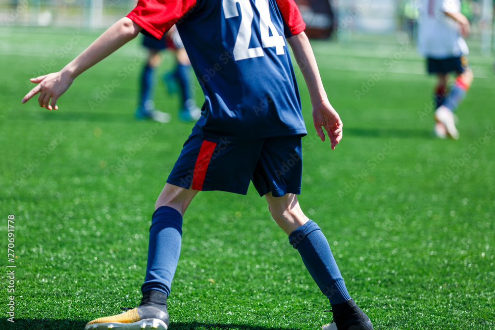 Boys at blue white sportswear run, dribble, attack on football field. Young soccer players with ball on green grass. Training, football, active lifestyle for kids Boys at blue white sportswear run, dribble, attack on football field. Young soccer players with ball on green grass. Training, football, active lifestyle for kids