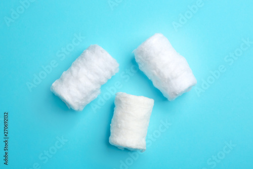 Three fluffy cotton rolls on color background, flat lay