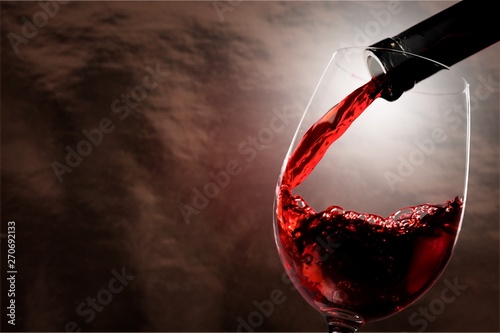 Red wine being poured in wineglass, closeup