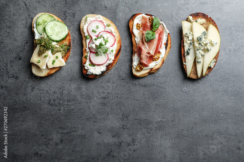 Different tasty bruschettas and space for text on grey background, flat lay