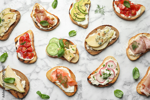 Different tasty bruschettas on marble background, flat lay