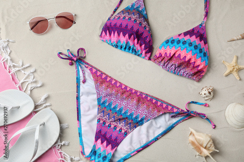 Flat lay composition with swimsuit and beach accessories on sand