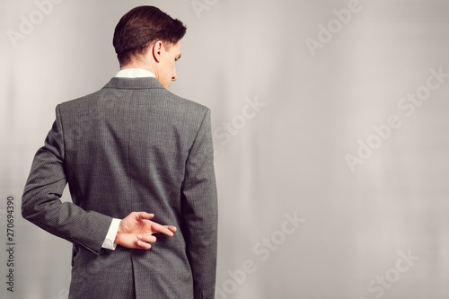 Businessman with his fingers crossed behind his back - concept for good luck or dishones