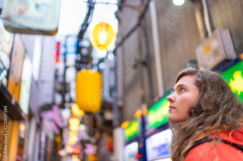 Tokyo, Japan Memory lane alley with decorations and yellow paper lamps lanterns bokeh background and young foreigner woman in Shinjuku area of city photo