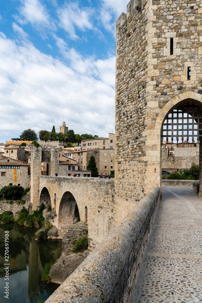 View along romanesque bridge over the Fluvia river, arches and defence towers showing