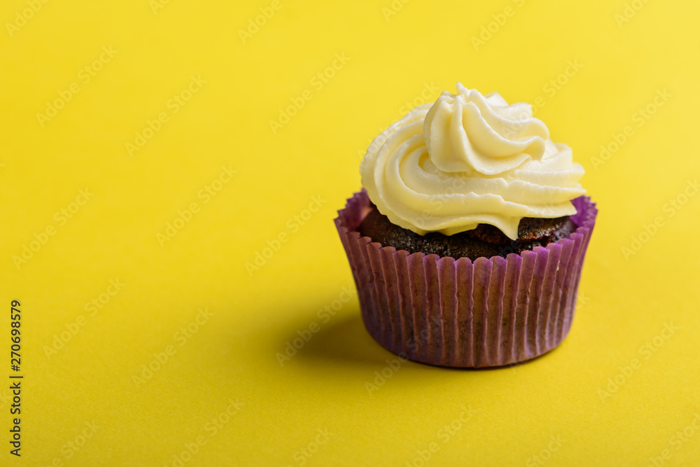 Cupcake in purple wrap on yellow background. Minimal. Copy space. Cupcake in purple wrap on yellow background. Minimal. Copy space.