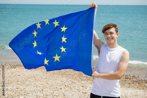 Caucasian male on a beach holding an EU flag