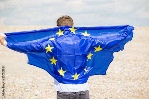 Caucasian male on a beach holding an EU flag