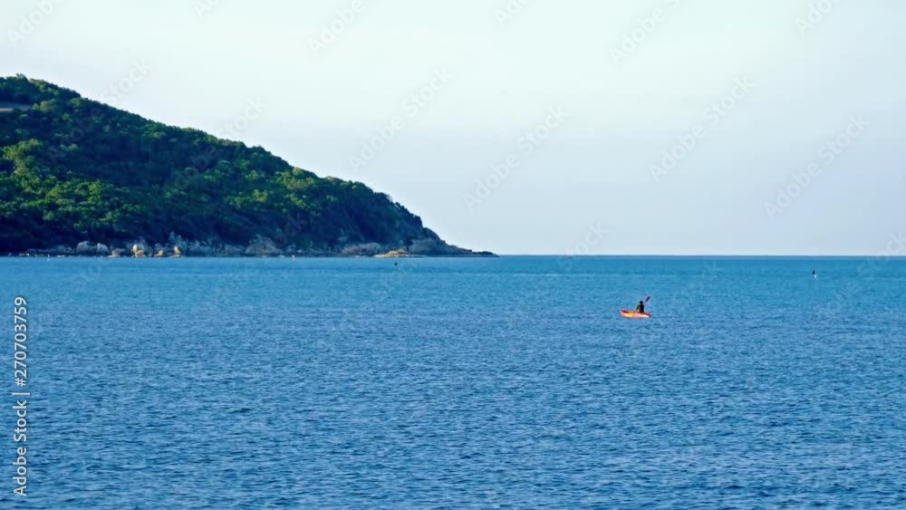 Rocky island and open sea with unrecognizable man kayaking Rocky island and open sea with unrecognizable man kayaking