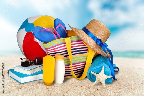 Straw hat, bag, flip flops on a tropical beach