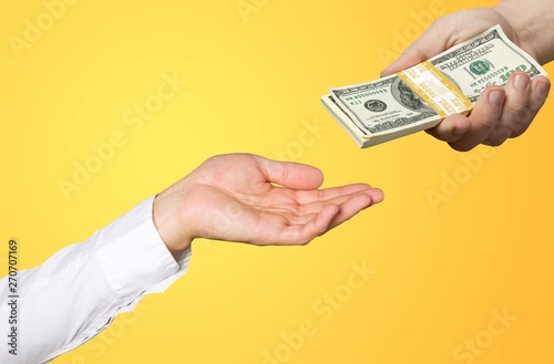 Man giving stack of dollars to woman on dark blurred background