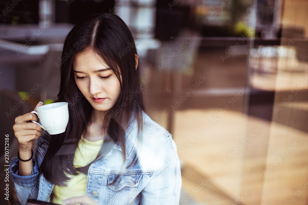 Asian woman with beautiful smile hold mobile phone during rest in coffee shop.Attractive woman drinking coffee.Reflection glass window. Asian woman with beautiful smile hold mobile phone during rest in coffee shop.Attractive woman drinking coffee.Reflection glass window.