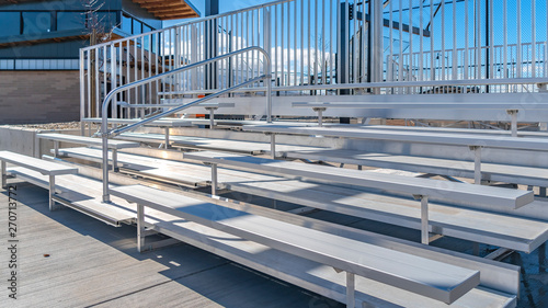 Panorama Bleachers with railings against a building and cloudy blue sky