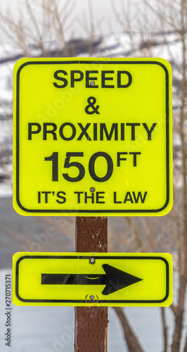 Vertical Close up of a bright yellow Speed and Proximity road sign with arrow