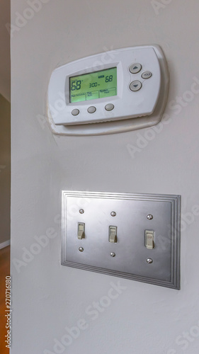 Vertical Air conditioning control panel and light switches mounted on a white wall