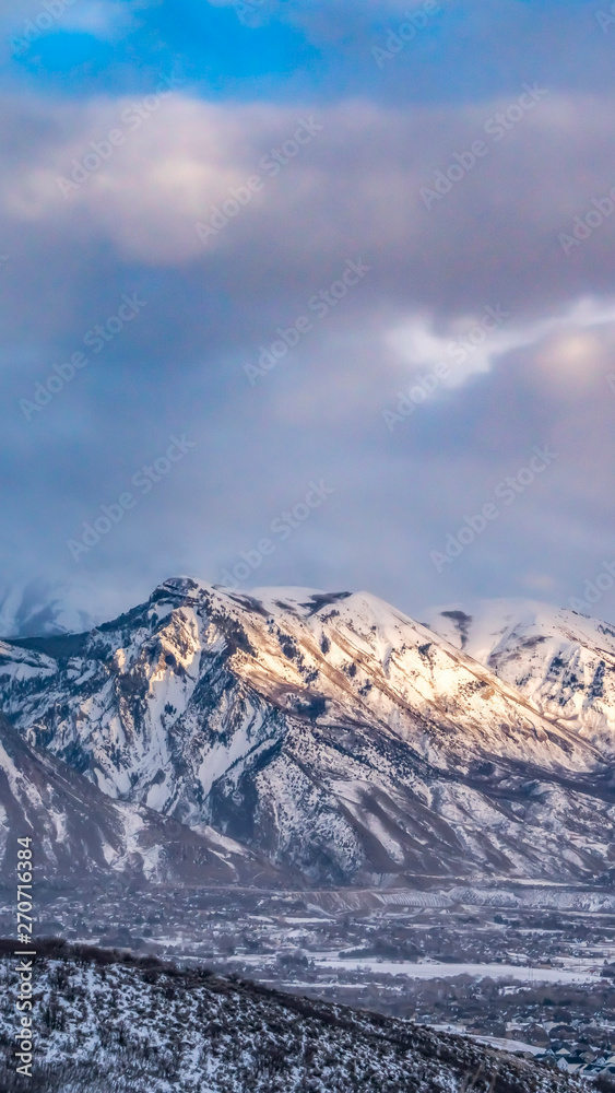 Vertical frame Majestic mountain covered with snow under blue sky with gray puffy clouds