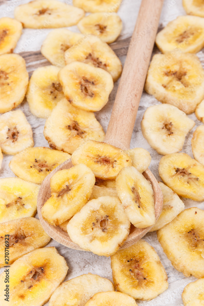 Dried organic banana chips with wooden spoon