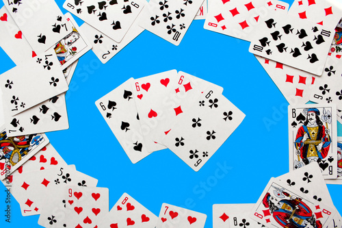 Four Playing Cards Isolated on blue Background. Close-up of playing cards.Showing Six from Each Suit - Hearts, Clubs, Spades and Diamonds. Space for text. Playing cards isolated on blue background.