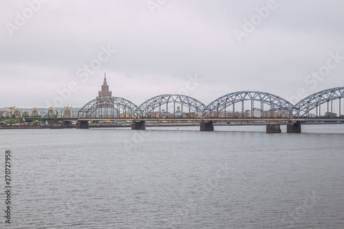 City Riga, Latvian Republic. Railway bridge with river Daugava and buildings. Urban view. May 27. 2019 Travel photo.