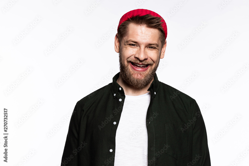 Portrait of cheerful man in perfect mood. Guy with kind smile wearing red trendy hat. Happy person posing in stylish outfit on studio background. Happiness and positivity concept Portrait of cheerful man in perfect mood. Guy with kind smile wearing red trendy hat. Happy person posing in stylish outfit on studio background. Happiness and positivity concept