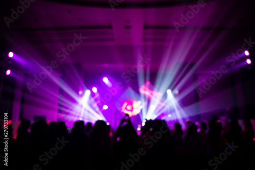 Defocused entertainment concert lighting on stage with people silhouette
