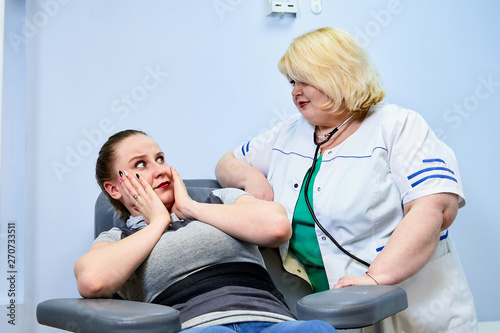 Experienced doctor fat woman taking care of a sick girl on the couch in the medical office