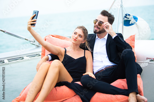 Handsome business man and woman on deck of yacht selfie with mobile phone