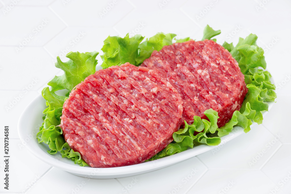 Raw mince meat beef burgers on a white plate Raw mince meat beef burgers on a white plate