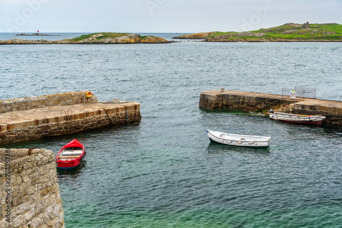 Coliemore Harbour in Dalkey village, Dublin, Ireland. Scenic little pier with three small fishing boats tied up behind the stone breakwater.  photo