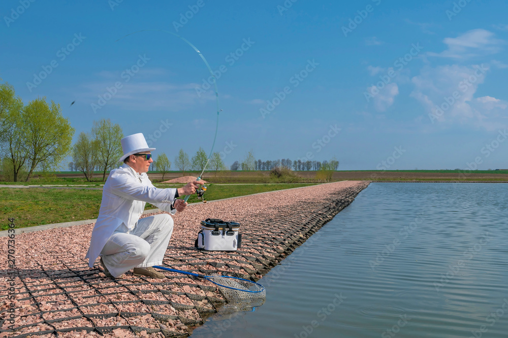 Exquisite fishing. Fisherman in white suit catch fish by spinning