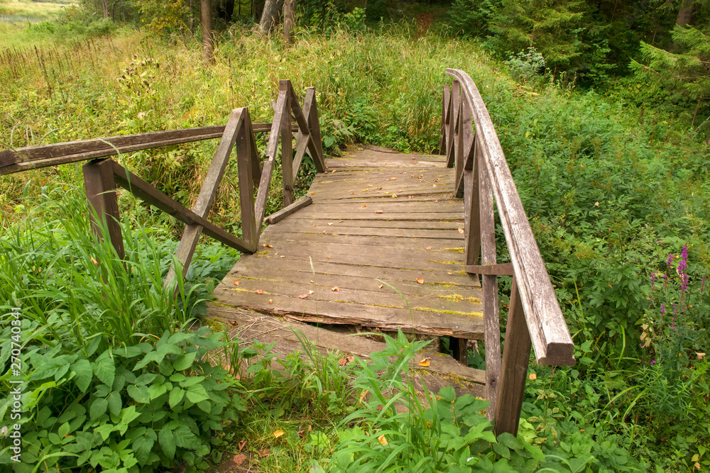 Old collapsing bridge over the overgrown stream Old collapsing bridge over the overgrown stream