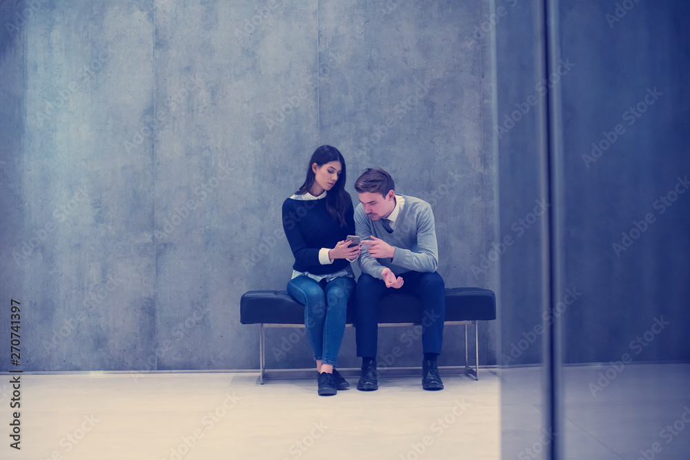 business couple using mobile phone while sitting on the bench business couple using mobile phone while sitting on the bench