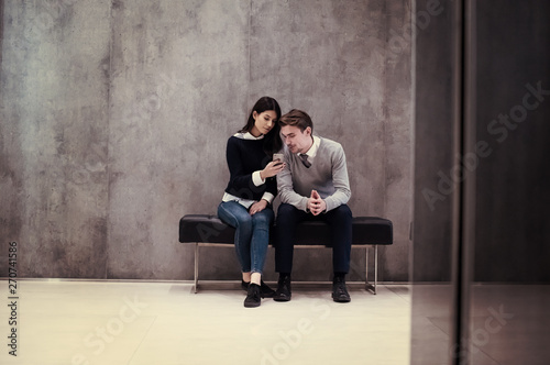 business couple using mobile phone while sitting on the bench