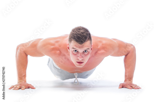 Sports man doing push ups isolated on a white background. Strong Athletic Man - Fitness Model showing his perfect body.