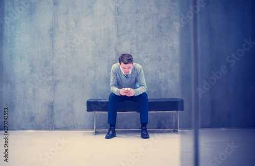 businessman using smart phone while sitting on the bench