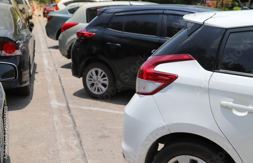 Closeup of rear, back side of white car with  other cars parking in outdoor parking lot beside the street. © Amphon