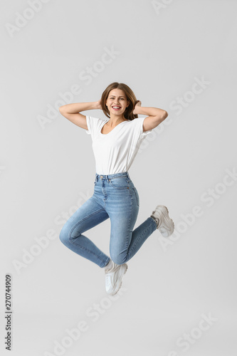 Jumping young woman in jean...