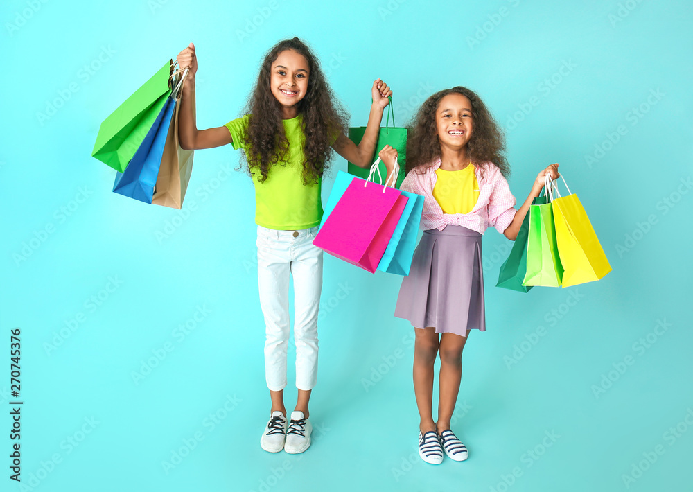 Cute African-American girls with shopping bags on color background Cute African-American girls with shopping bags on color background