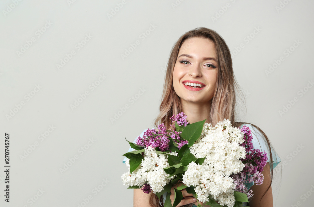Beautiful young woman with lilac flowers on light background Beautiful young woman with lilac flowers on light background