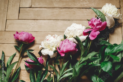 Beautiful pink and white peonies on rustic wooden floor   flat lay. Floral decor and arrangement. Gathering flowers. Rural still life  countryside flowers