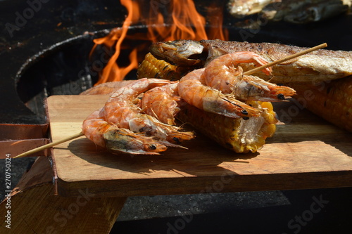 Grilled shrimps, fish and corn on a wooden board