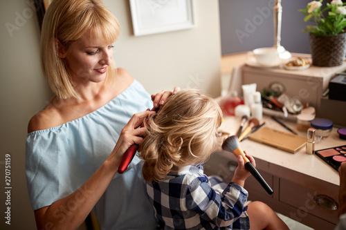 Mom brushing hair to her daughter