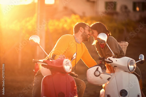 Romantic man and woman riding on a scooter in European..